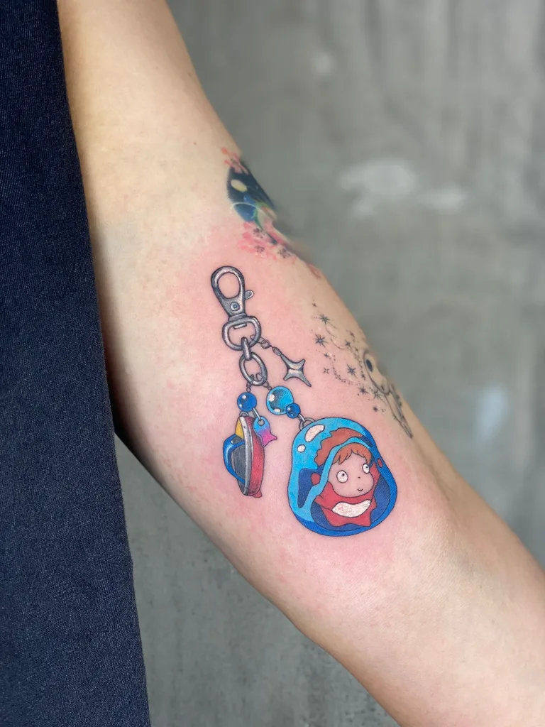 Keychain charm tattoo design, anime style, on the forearm, with a cute character and small glass beads, in vibrant color