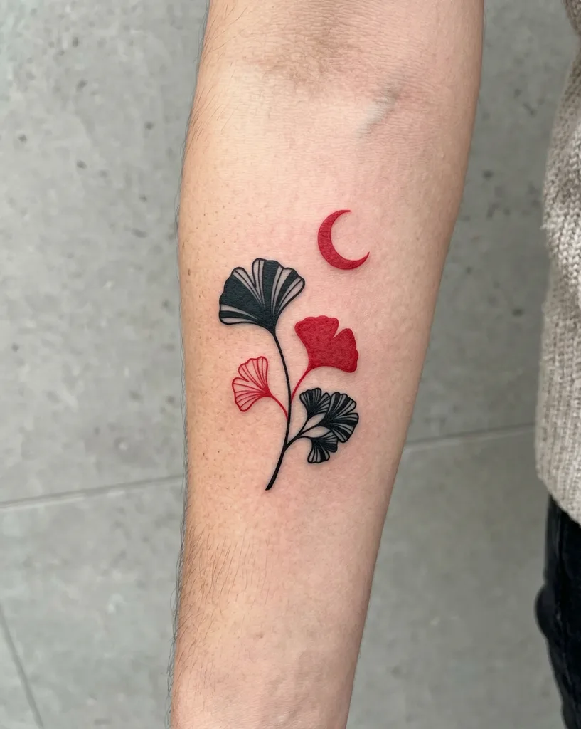 Ginkgo leaves tattoo design for women, minimalist style, on the forearm, in red and black with a red crescent moon