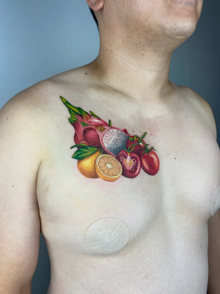 realism-chest-men-fruits-25 Fruits tattoo design for men, realism style, on the full chest, a cluster of dragon fruit, plums, strawberries and a citrus slice in full color on one pec